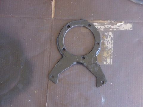 1971 Ford Bronco - A black metal bracket with a circular opening and mounting holes is shown against a brown surface.
