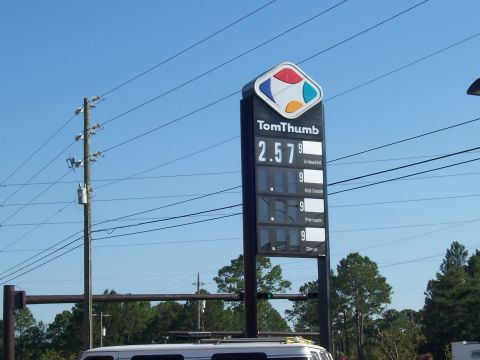 1995 Ford Bronco - A TomThumb gas station sign displays current fuel prices under a clear blue sky.