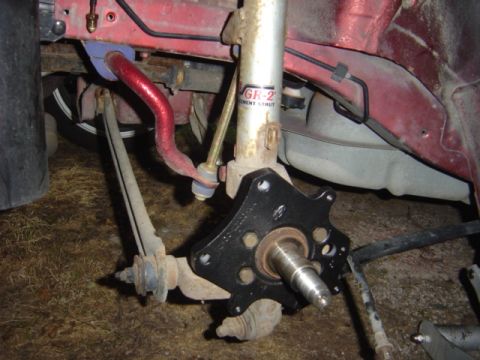 1998 Ford Taurus - Close-up view of a red car's front suspension system, highlighting the sway bar and strut assembly.