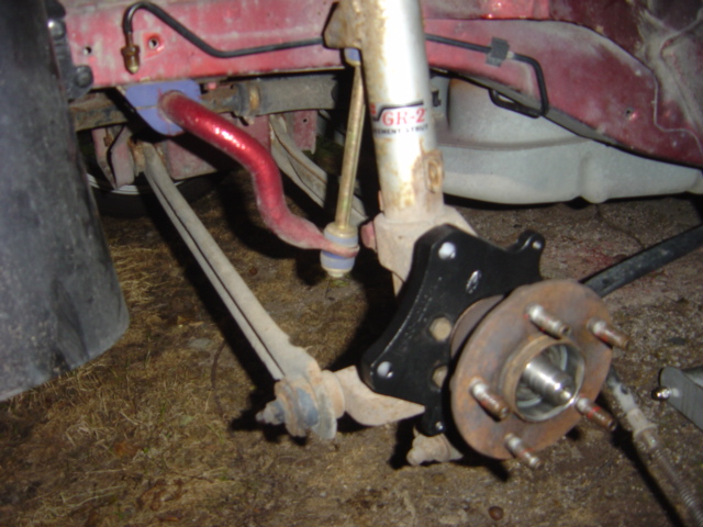 Close-up of a car's front suspension assembly, showing the brake rotor, hub, sway bar, and shock absorber
