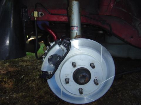 1998 Ford Taurus - Close-up view of a vehicle's brake caliper and rotor assembly, a slotted rotor.