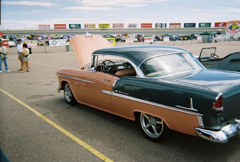 1972 Ford Ranchero - A two-tone peach and dark green 1955 Chevrolet Bel Air is parked with its hood open at an outdoor event.