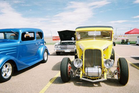 1972 Ford Ranchero - A bright yellow hot rod is parked in front of other vehicles under a partly cloudy sky.