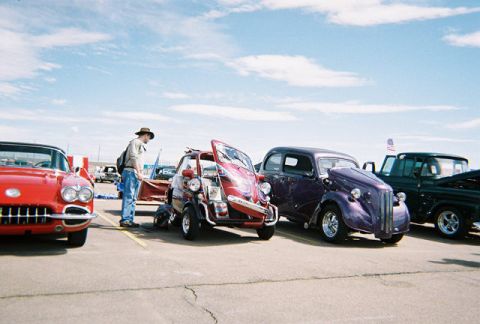 1972 Ford Ranchero - A collection of classic vehicles are displayed outdoors on a sunny day, with a person examining one of the cars.