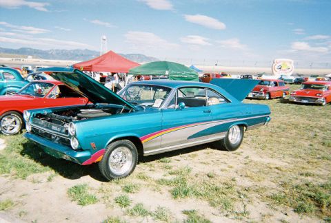 1972 Ford Ranchero - A turquoise 1966 Ford Falcon is displayed with its hood open at an outdoor car show event.