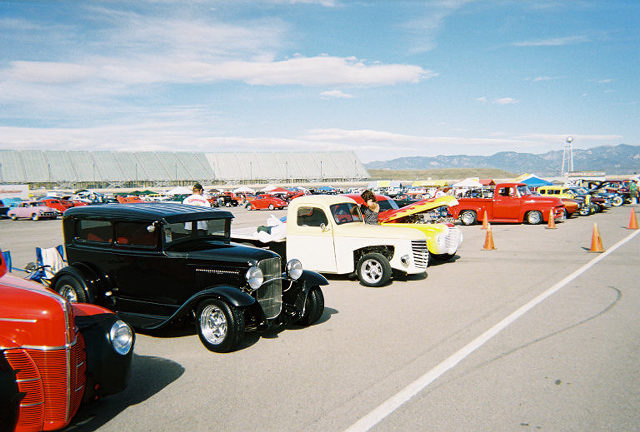 Black sedan parked at a car show with other vehicles in the background