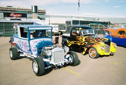 1972 Ford Ranchero - A black hot rod pickup truck with flame graphics is parked next to a blue hot rod.