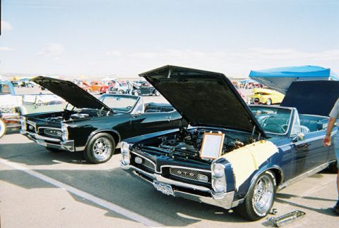 1972 Ford Ranchero - Two classic Pontiac convertibles are displayed with their hoods open at an outdoor car show.