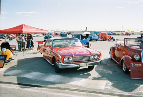 1972 Ford Ranchero - A red custom coupe with flame decals is displayed at an outdoor car show next to other vehicles.