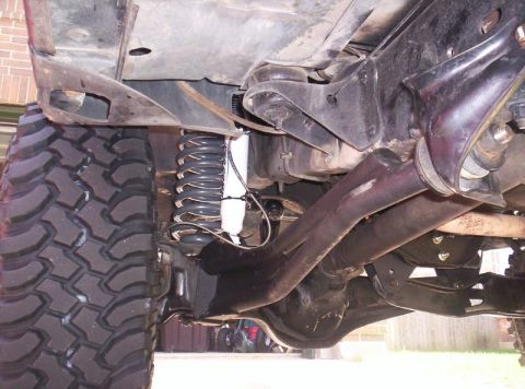 1984 Ford F-150 - This image shows the undercarriage of a 1984 Ford F-150, highlighting its lifted suspension and off-road tires.