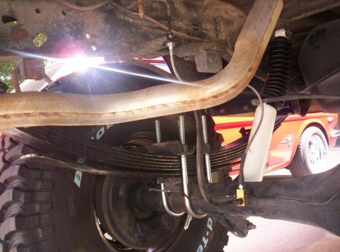 1984 Ford F-150 - Close-up of a truck's rear suspension components, with another vehicle in the background.