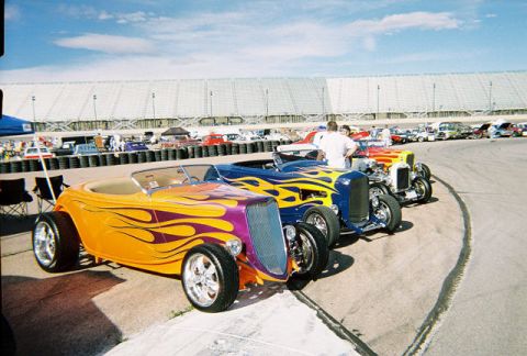 1972 Ford Ranchero - Several custom hot rod cars with flame paint jobs are lined up at an outdoor event.