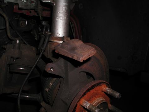 1992 Ford Taurus - Close-up of a corroded vehicle brake system, showing wear and tear on the components.