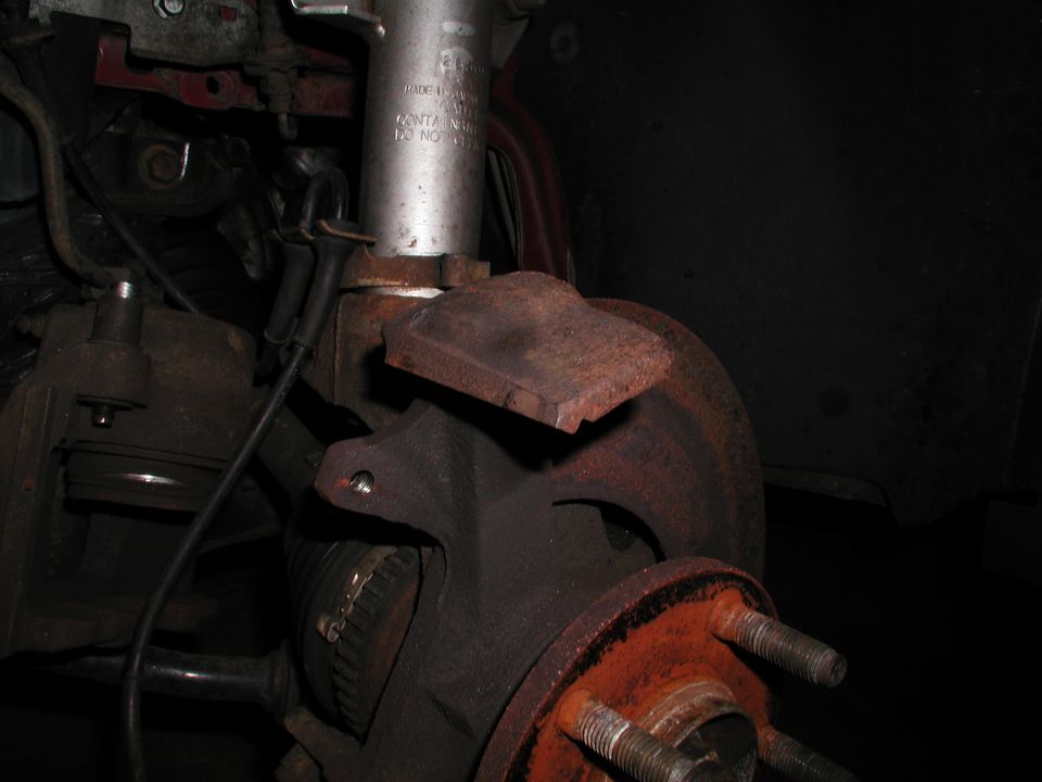 Rusty car brake assembly with rotor and caliper visible