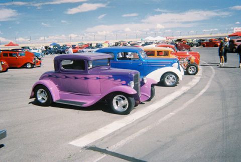 1972 Ford Ranchero - Several custom cars are lined up at an outdoor event under a partly cloudy sky.