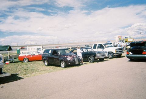 1972 Ford Ranchero - Several vehicles are parked on a sunny day with a racetrack in the background.