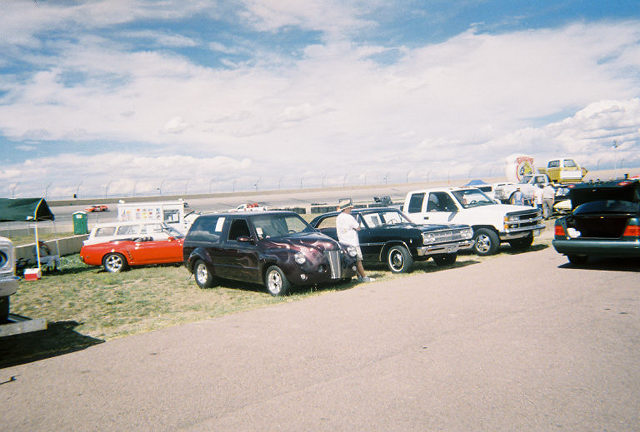 Customized dark purple SUV with flame paint parked next to other vehicles at an outdoor event