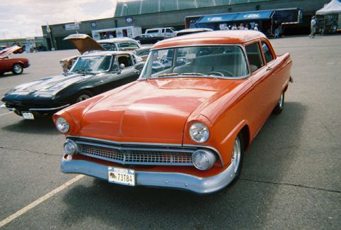 1972 Ford Ranchero - An orange sedan from 1955 is parked at an outdoor event, with other vehicles visible in the background.