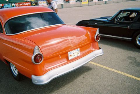 1972 Ford Ranchero - Rear view of an orange 1955 Ford Fairlane parked next to a black car.