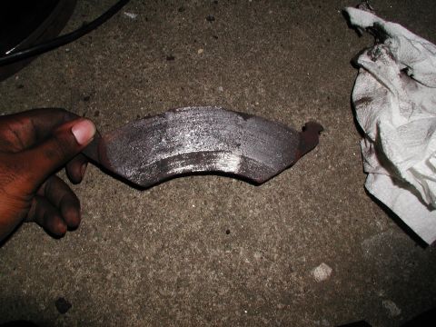 1992 Ford Taurus - Worn brake pad removed from a vehicle, showing significant metal scoring and wear.
