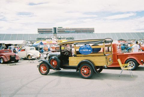 1972 Ford Ranchero - A vintage pickup truck with a wooden bed and surfboard is parked at an outdoor event with other vehicles.