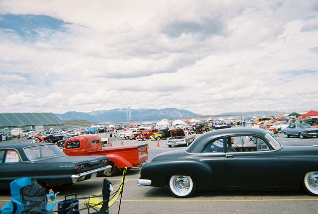 Cars parked at an outdoor event with mountains in the background