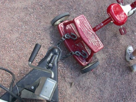 1994 Ford Bronco - A red Radio Flyer wagon is chained to a trailer hitch on a gravel surface.