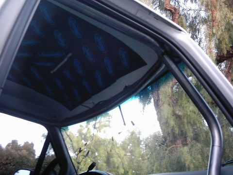 1978 Ford Bronco - The interior of a vehicle shows a roll cage and soundproofing on the headliner.
