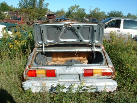1978 Ford Mustang II - This car's rear end and open trunk are visible in a junkyard setting.
