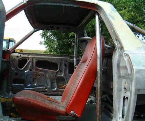1967 Ford Ranchero - The interior of a 1967 Ford Ranchero shows a red seat and a roll cage, with the door removed.