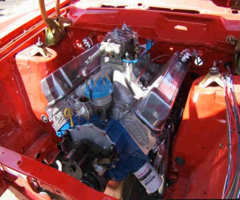 1967 Ford Ranchero - The engine bay of a classic car features a V8 engine with polished chrome valve covers and bright blue ignition components.
