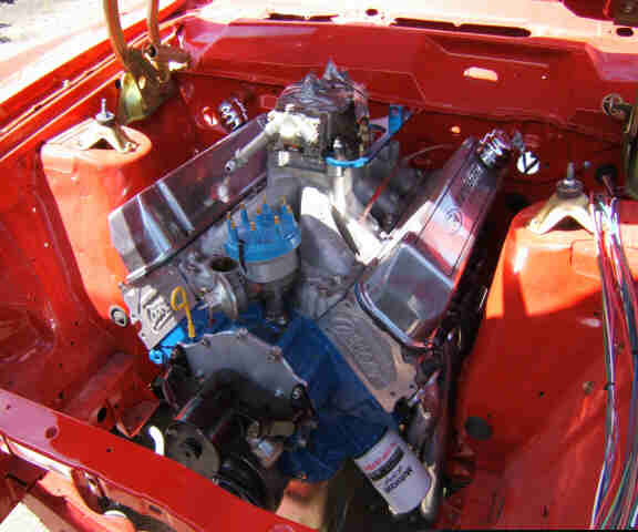 V8 engine with polished valve covers and blue distributor in red engine bay