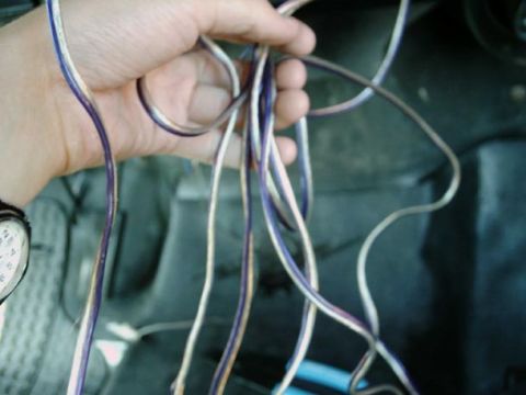 1971 Ford F-100 - A hand manipulates a tangle of electrical wires, suggesting work within a vehicle's interior.
