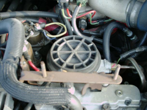 Round ribbed black fuel filter cover installed in a diesel engine valley