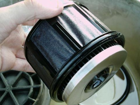 2002 Ford F-250 - A black fuel filter with a silver base is held by a hand, with another filter component visible in the background.