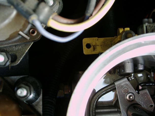 Close-up engine bay detail with pink highlight circle around a canister drain fitting and wiring