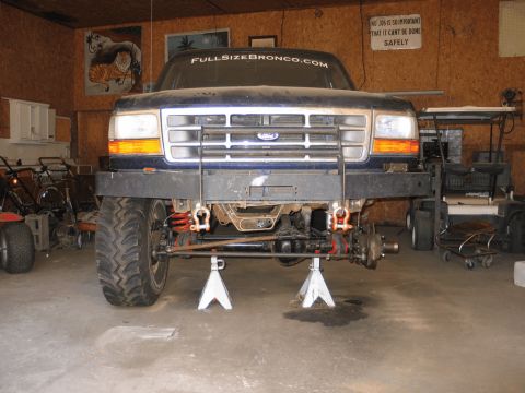 1995 Ford Bronco - Front view of a blue Ford truck with its front end lifted on jack stands, showing mechanical components.