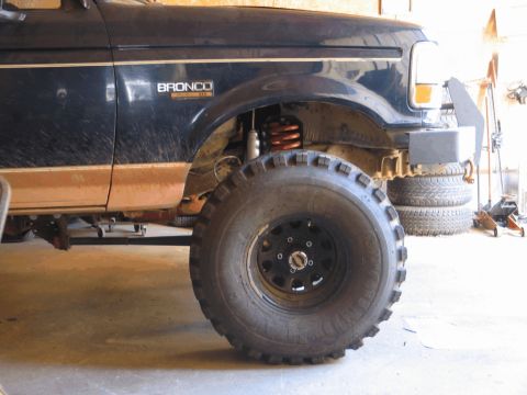 1995 Ford Bronco - Front view of a dark blue 1995 Ford Bronco, showing its large off-road tire and lifted suspension.