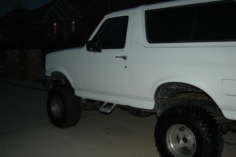 1992 Ford Bronco - A white 1992 Ford Bronco is shown from the side, lifted with large off-road tires.
