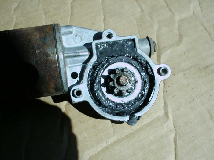 Disassembled starter motor showing pinion gear and old dark grease