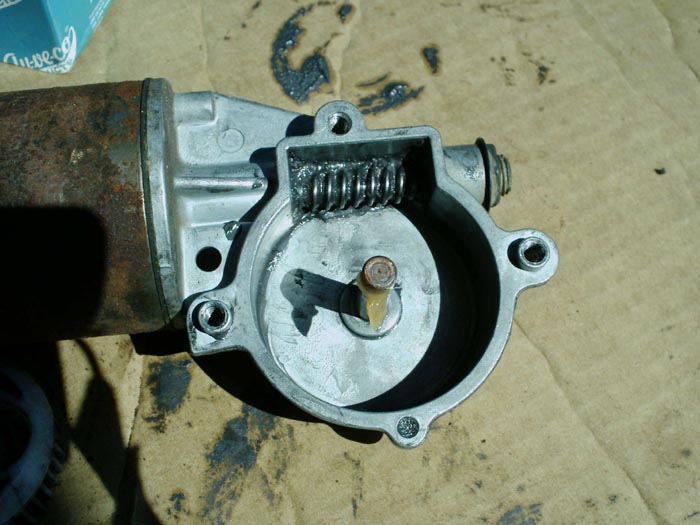 Opened wiper motor gearbox showing worm gear and output shaft, attached to rusty motor housing