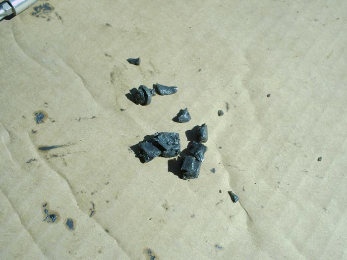 Broken dark metal fragments on cardboard