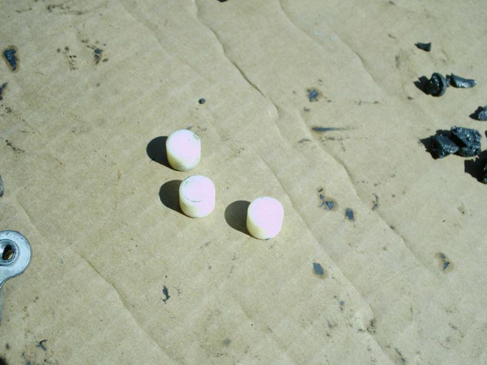 Three small cream and pink cylindrical pins on cardboard