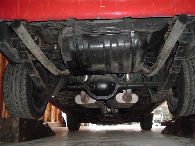 Undercarriage view of a red car showing leaf springs, exhaust, and differential