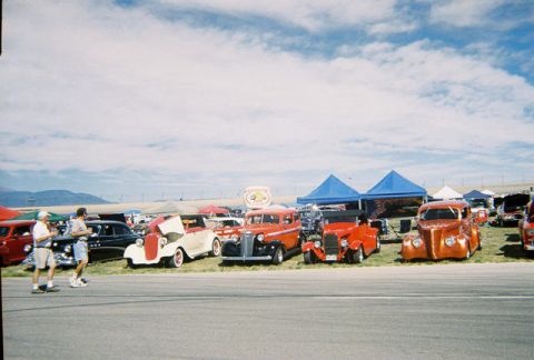 1972 Ford Ranchero - A car show with multiple vintage vehicles on display under a partly cloudy sky.