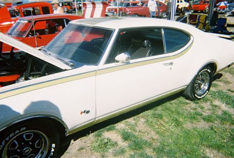 1972 Ford Ranchero - A white 1970 Oldsmobile Cutlass Supreme is shown with its hood open at an outdoor car event.