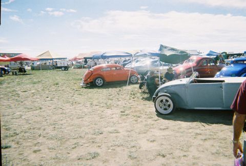 1972 Ford Ranchero - An orange custom coupe is parked at an outdoor event with other vehicles and tents in the background.