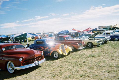 1972 Ford Ranchero - A variety of custom cars are displayed at an outdoor event on a sunny day.