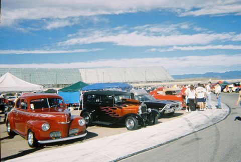 1972 Ford Ranchero - A red coupe from the 1940s is parked at an outdoor event with other vehicles and tents in the background.