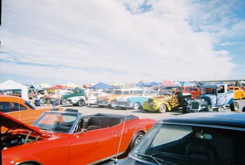 1972 Ford Ranchero - A variety of classic vehicles are displayed at an outdoor car show, with tents and a cloudy sky in the background.